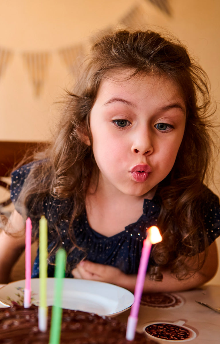 niña soplando sus belas de cumpleaños